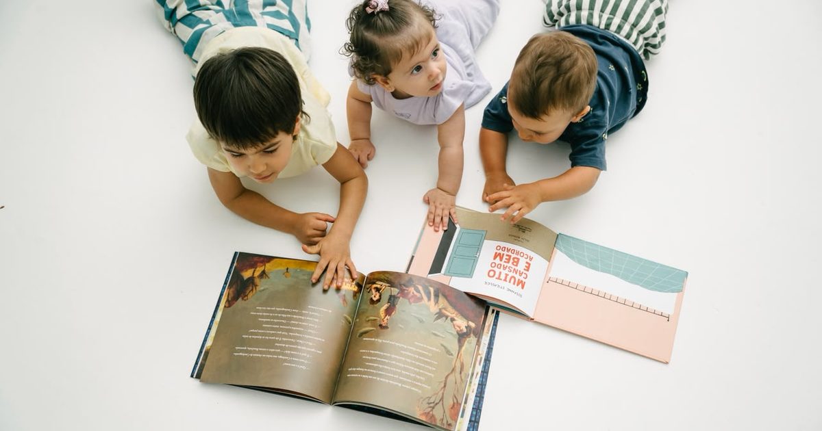 Criança pequena folheando um livro ilustrado no chão